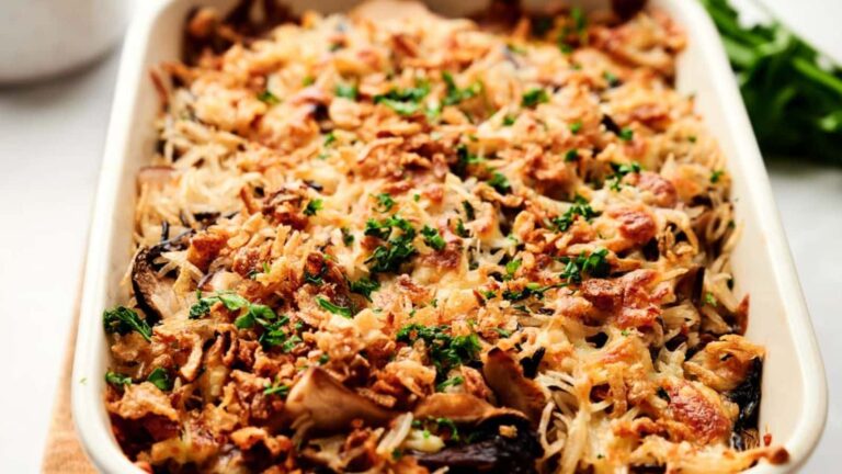 A casserole dish filled with a golden-brown baked dish topped with parsley and crispy fried onions.