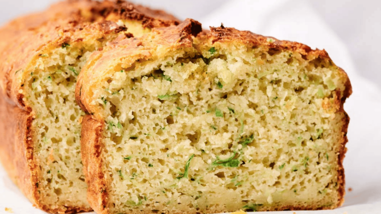 Close-up of two slices of freshly baked zucchini bread with a golden-brown crust, revealing a moist and textured interior.