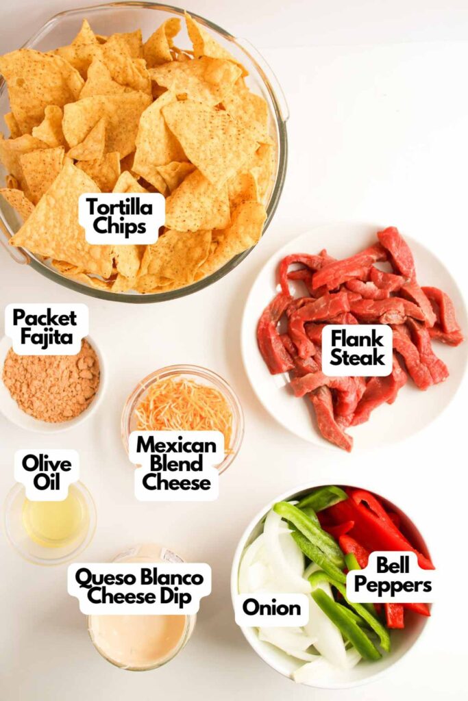 Ingredients include tortilla chips, seasoned flank steak for the perfect steak fajita nachos, bell peppers, onion, Mexican blend cheese, queso blanco cheese dip, olive oil, and fajita seasoning.
