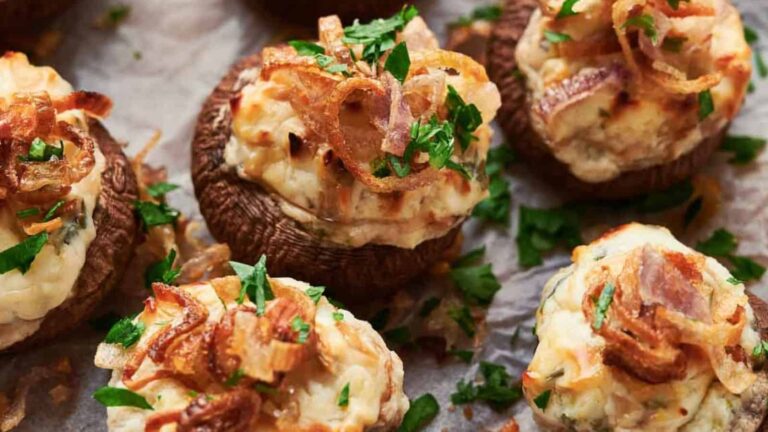 Stuffed mushrooms topped with crispy shallots and parsley on parchment paper.