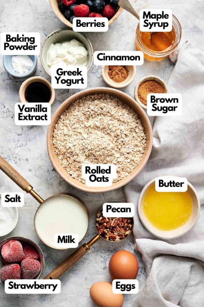 Ingredients on a surface include rolled oats, berries, maple syrup, cinnamon, brown sugar, butter, pecans, eggs, milk, strawberries, salt, vanilla extract, Greek yogurt, and baking powder.
