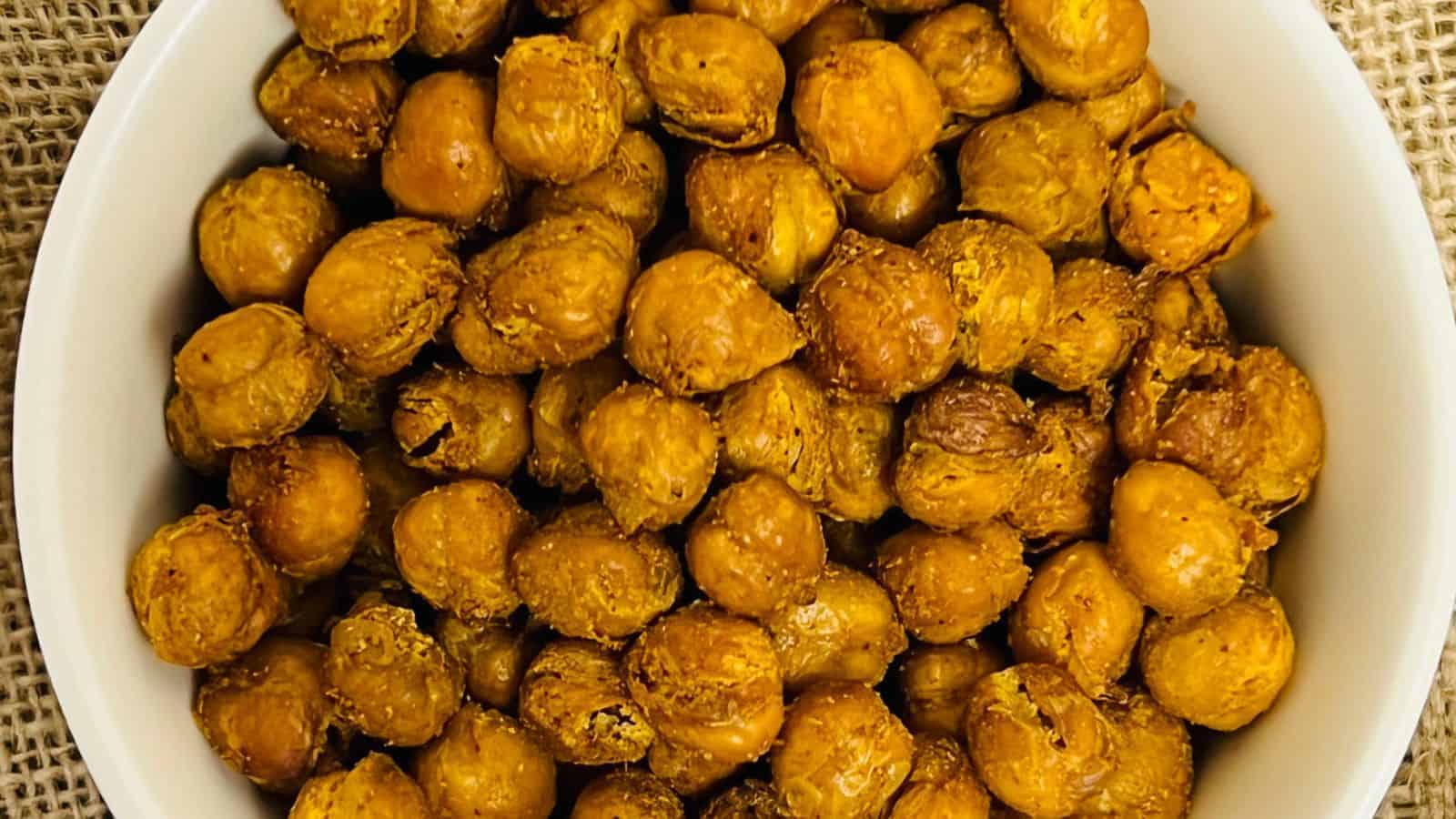 A bowl of roasted chickpeas with seasoning, viewed from above.