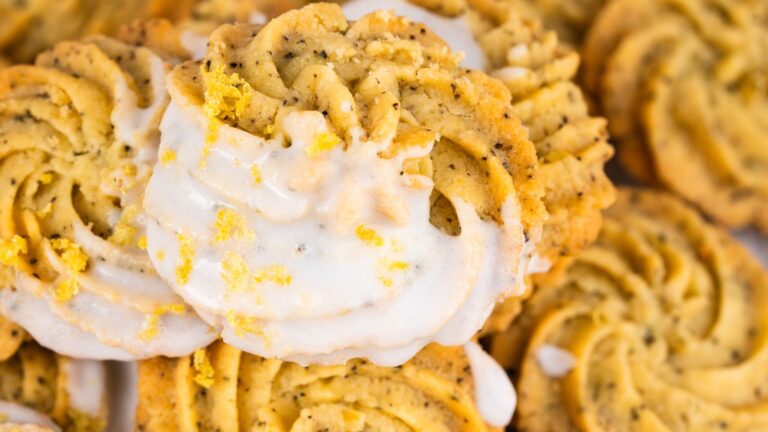 Close-up of spiral lemon poppy seed cookies drizzled with white icing and garnished with lemon zest.