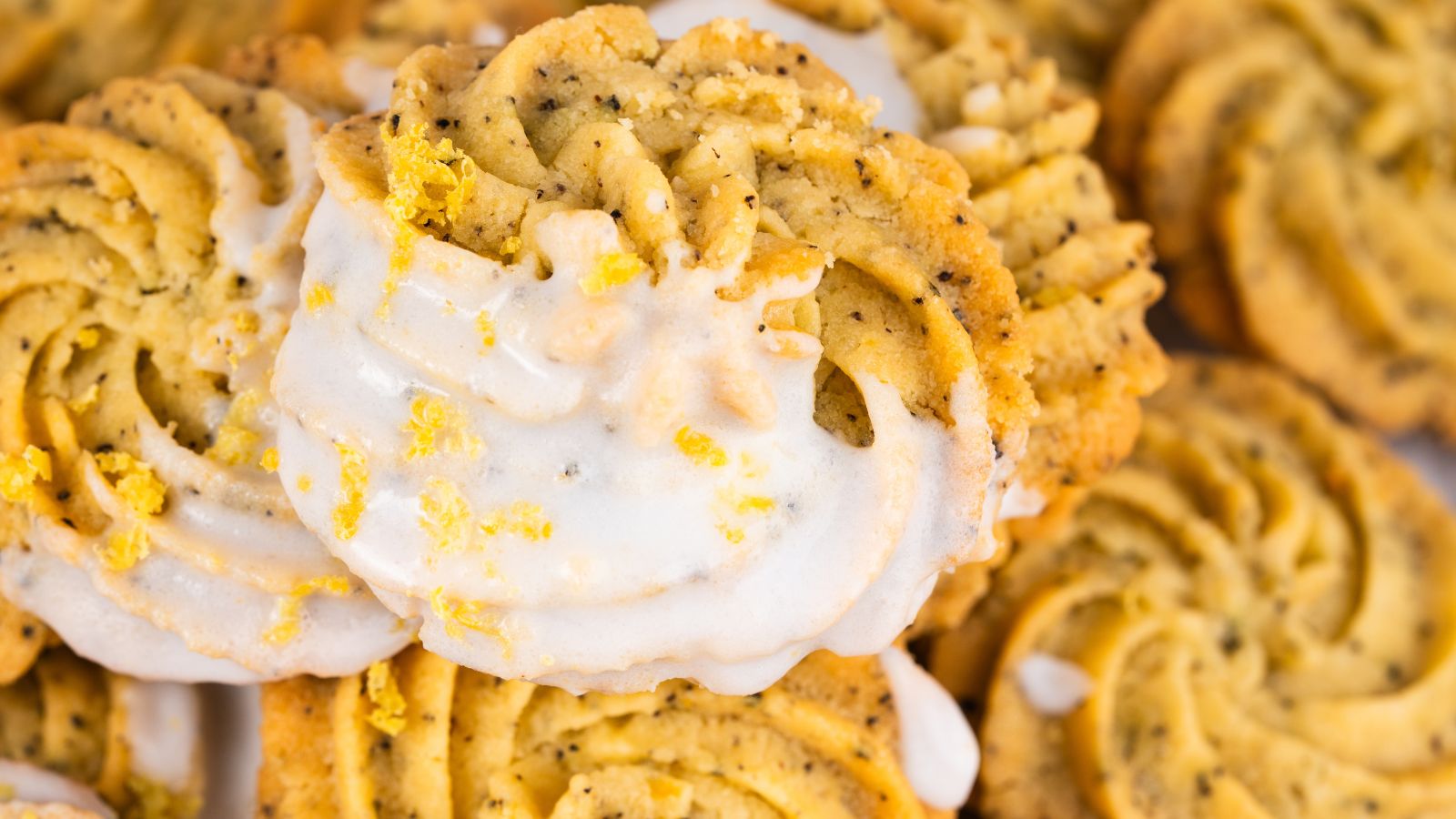 Close-up of spiral lemon poppy seed cookies drizzled with white icing and garnished with lemon zest.