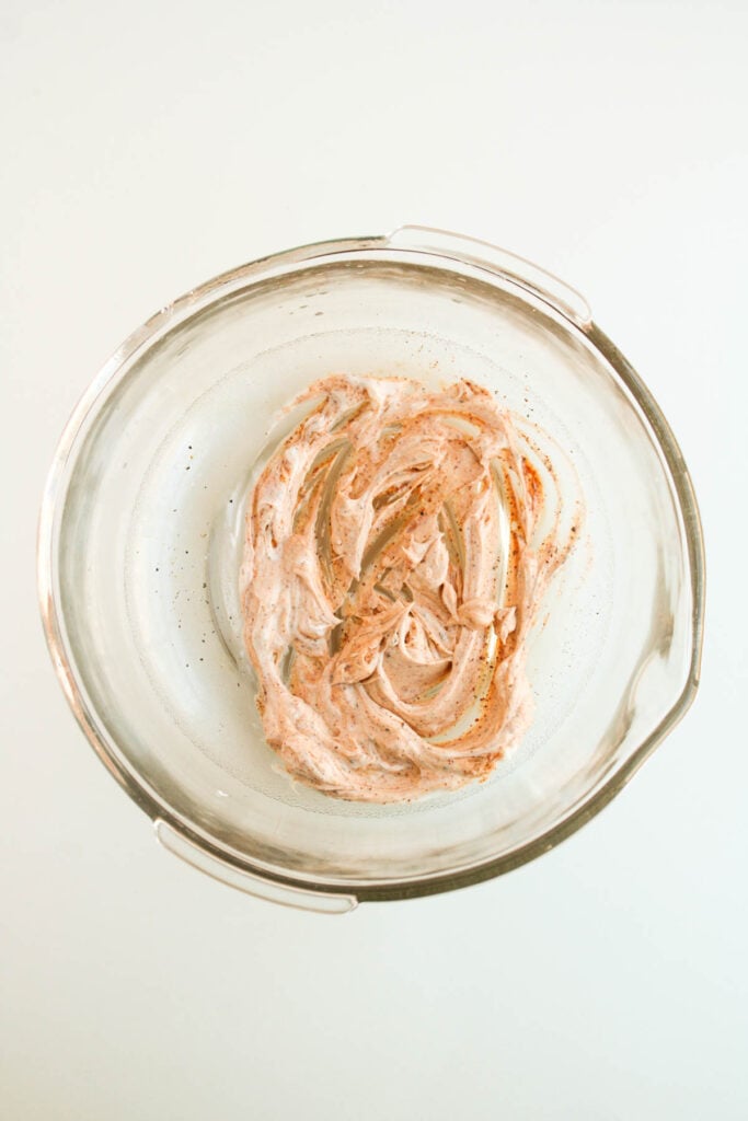 A glass bowl holding a creamy blend with a sprinkle of cinnamon, reminiscent of the rich flavors found in Mexican street corn, viewed from above.
