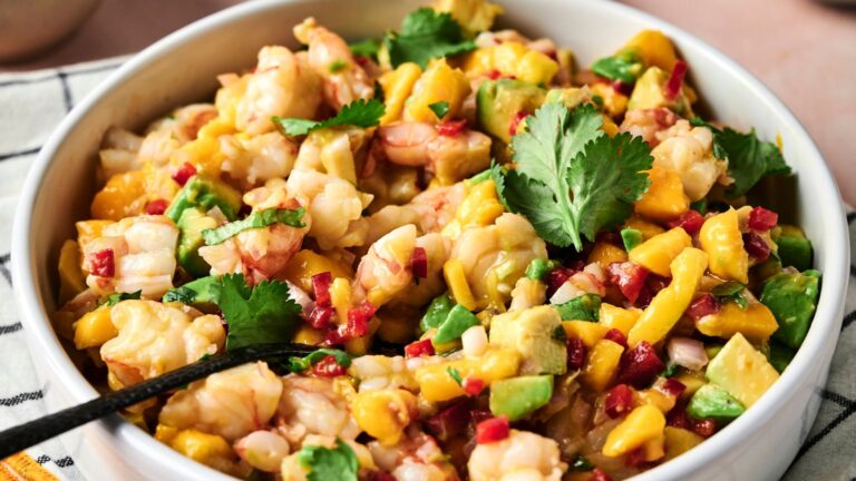 A bowl of shrimp ceviche mixed with avocado, mango, red onion, cilantro, and diced red chili peppers.