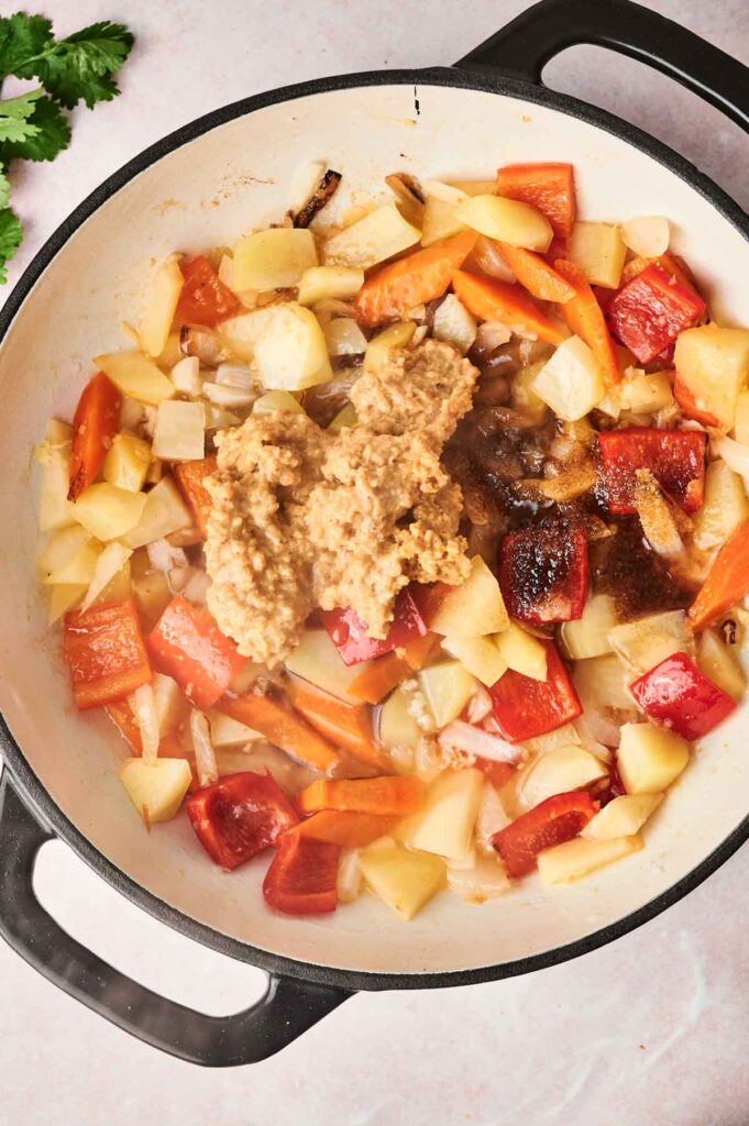 Chopped vegetables and a spoonful of Massaman curry seasoning mix in a pan, shown from above.