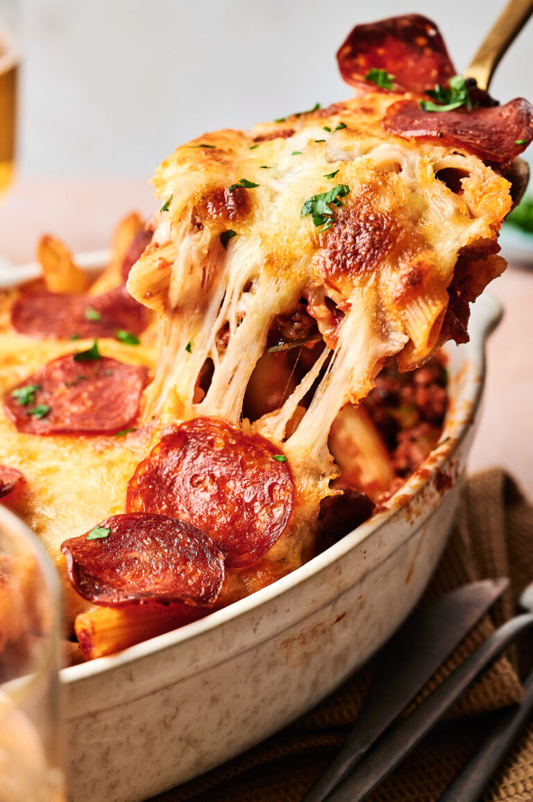 A delightful pizza casserole, this cheese-covered pasta bake with pepperoni slices is being served from a baking dish.