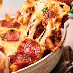A delightful pizza casserole, this cheese-covered pasta bake with pepperoni slices is being served from a baking dish.