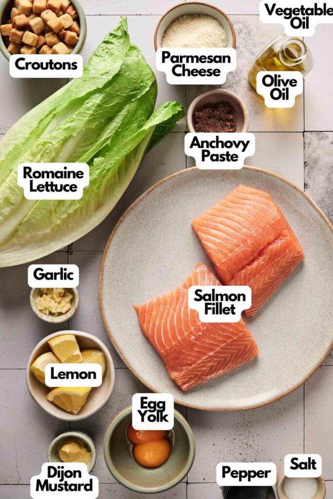 Ingredients for a delicious Salmon Caesar Salad: romaine lettuce, salmon fillet, croutons, Parmesan cheese, anchovy paste, vegetable oil, olive oil, garlic, lemon, egg yolk, Dijon mustard, pepper, salt.