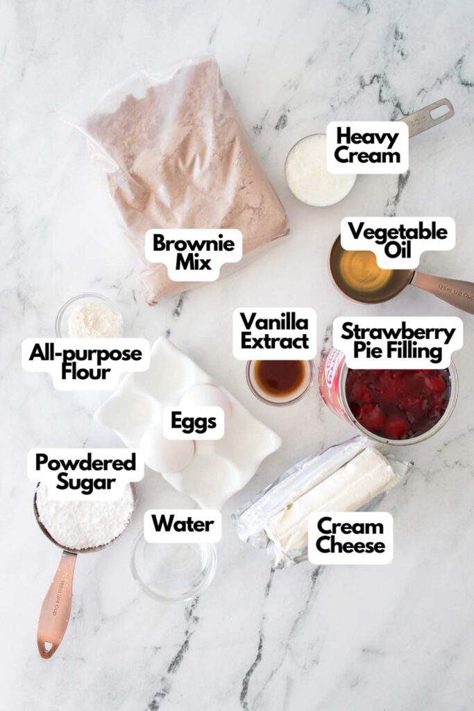 Strawberry Cheesecake Brownies ingredients—brownie mix, heavy cream, vegetable oil, flour, eggs, vanilla extract, strawberry pie filling, powdered sugar, water, and cream cheese—are beautifully arranged on a marble surface.