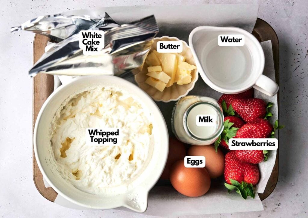 A tray with labeled ingredients for Strawberry Poke Cake: white cake mix, butter, water, whipped topping, milk, eggs, and fresh strawberries.