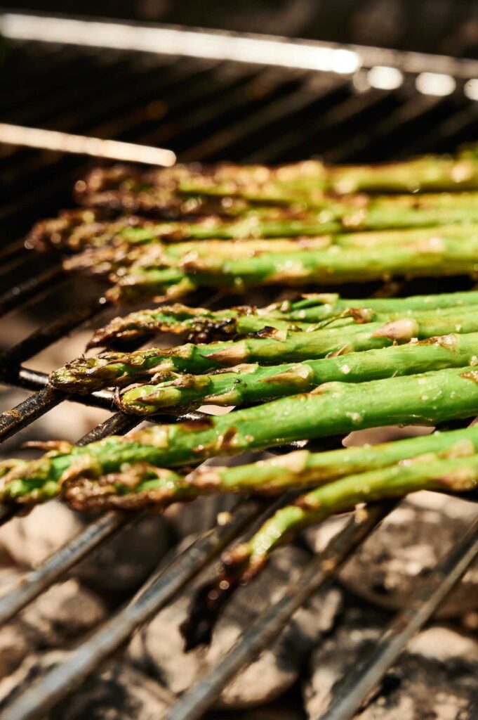Grilled asparagus cooks to perfection over hot coals on an outdoor barbecue grill, creating deliciously smoky grilled asparagus spears.