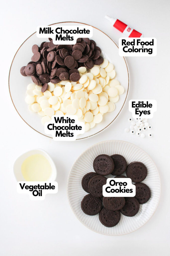 A plate with Ladybug Chocolate Covered Oreos, milk and white chocolate melts, a tube of red food coloring, edible eyes, a small bowl of vegetable oil, and a plate of Oreo cookies displayed on a white surface.