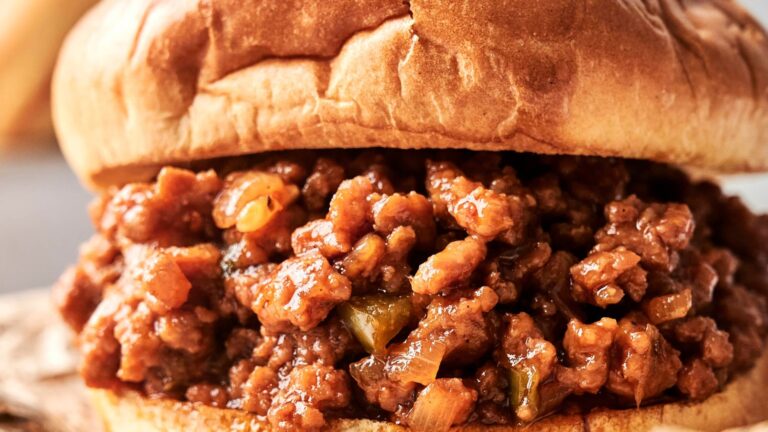 Close-up of a sloppy joe sandwich with ground meat in a rich tomato sauce on a soft, lightly toasted bun.