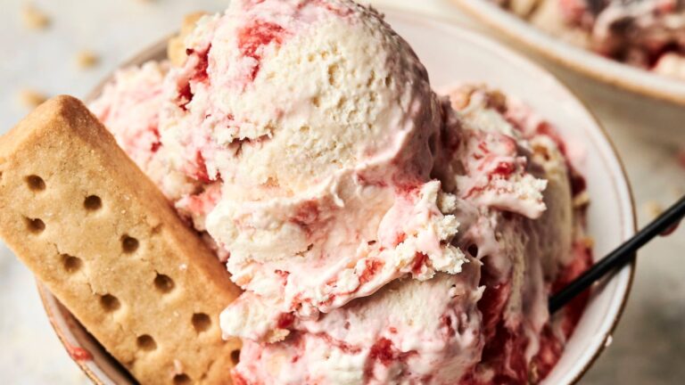 A bowl of strawberry swirl ice cream with a rectangular shortbread biscuit and a spoon.