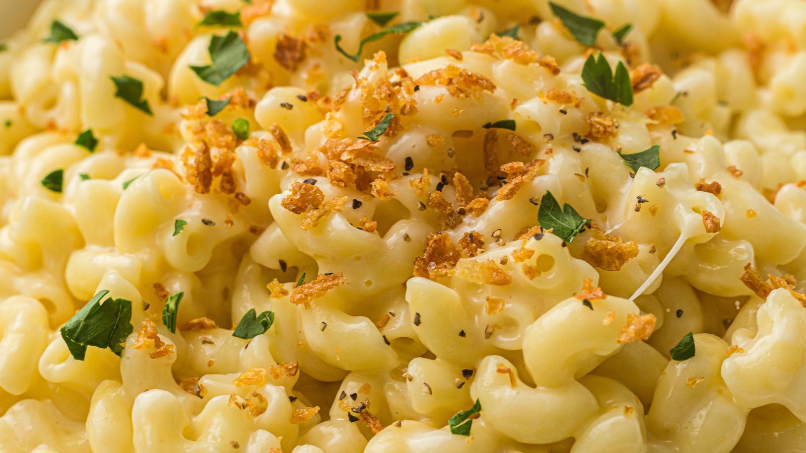 Close-up of creamy macaroni and cheese topped with crispy breadcrumbs and chopped parsley.