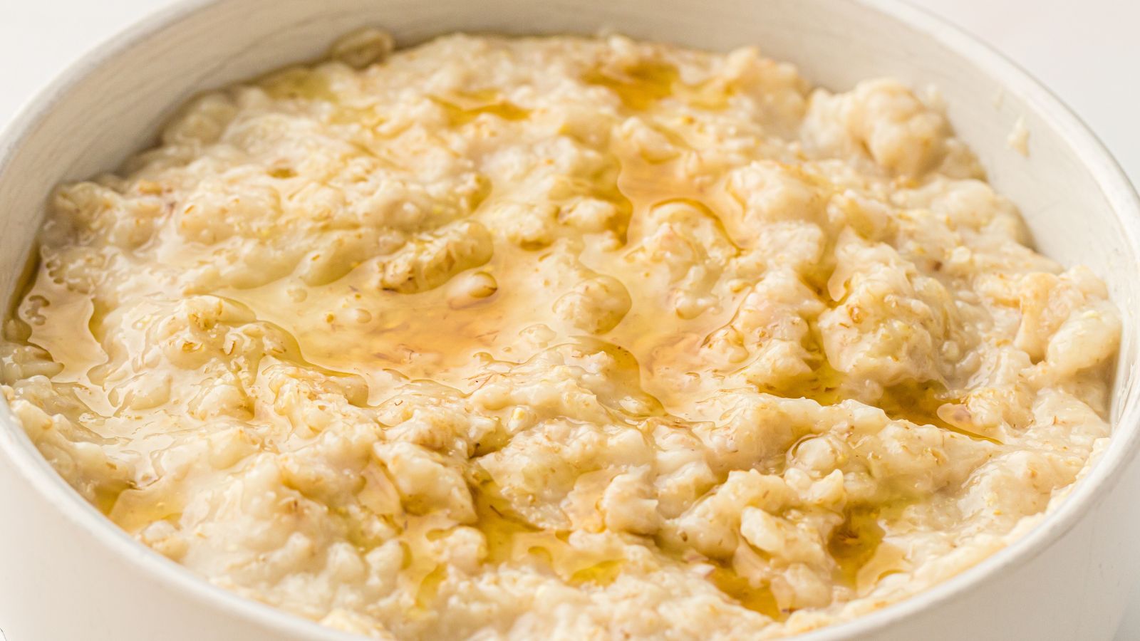 A bowl of oatmeal porridge topped with a drizzle of honey.