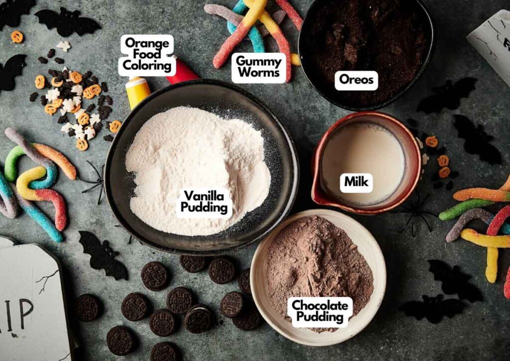 Bowls of vanilla pudding mix, chocolate pudding mix, milk, orange food coloring, gummy worms, and Oreos arranged on a table with Halloween-themed decorations&mdash;perfect ingredients for fun and festive Halloween Dirt Cups.