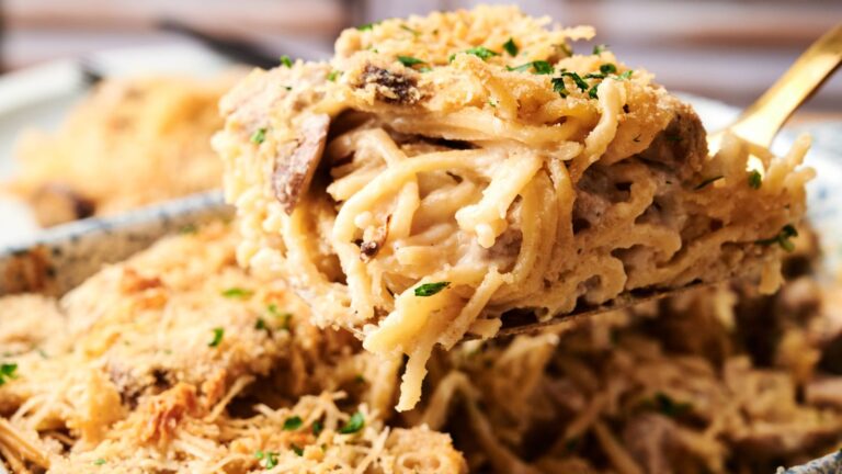 A close-up of a serving of baked spaghetti casserole with a creamy sauce, shredded chicken, and a crispy breadcrumb topping.