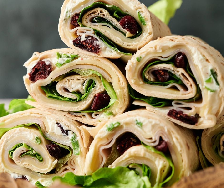 Six Turkey Pinwheels tortilla wraps filled with lettuce, cream cheese, and dried cranberries, stacked in a pyramid shape.