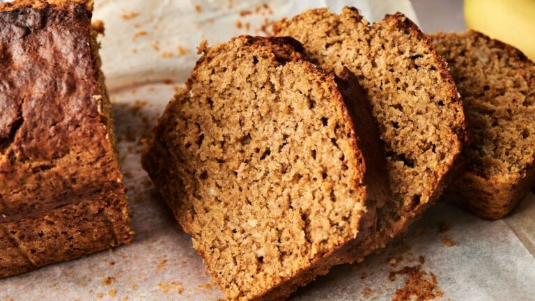 Sliced loaf of banana bread resting on parchment paper, showing its moist and textured interior.