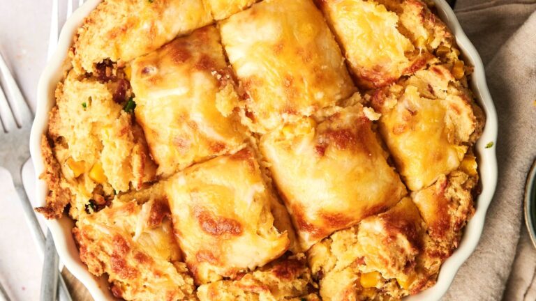 A baked dish with a golden, cheesy crust cut into square pieces, showing a filling with visible corn and other ingredients.