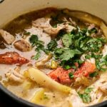 A bowl of Air Fryer Chicken Soup with potatoes, carrots, shredded chicken, herbs, and broth, garnished with chopped cilantro.