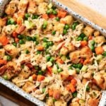 A casserole dish filled with a baked mixture of bread cubes, shredded chicken, peas, carrots, celery, and a creamy sauce—just like an Air Fryer Chicken and Stuffing Casserole.