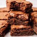 A close-up of four stacked Protein Brownies with a cracked, fudgy top and dense, moist interior.