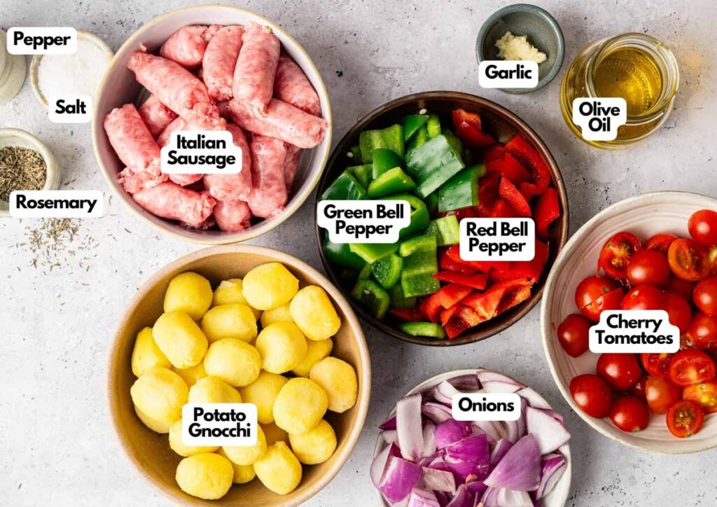 Bowls of Italian sausage, potato gnocchi, green and red bell peppers, cherry tomatoes, onions, and seasonings—perfect for making Sheet Pan Gnocchi with a medley of fresh veggies and savory flavors.
