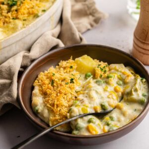 A bowl of creamy Easter Casserole topped with golden breadcrumbs sits next to a baking dish filled with the same comforting casserole.