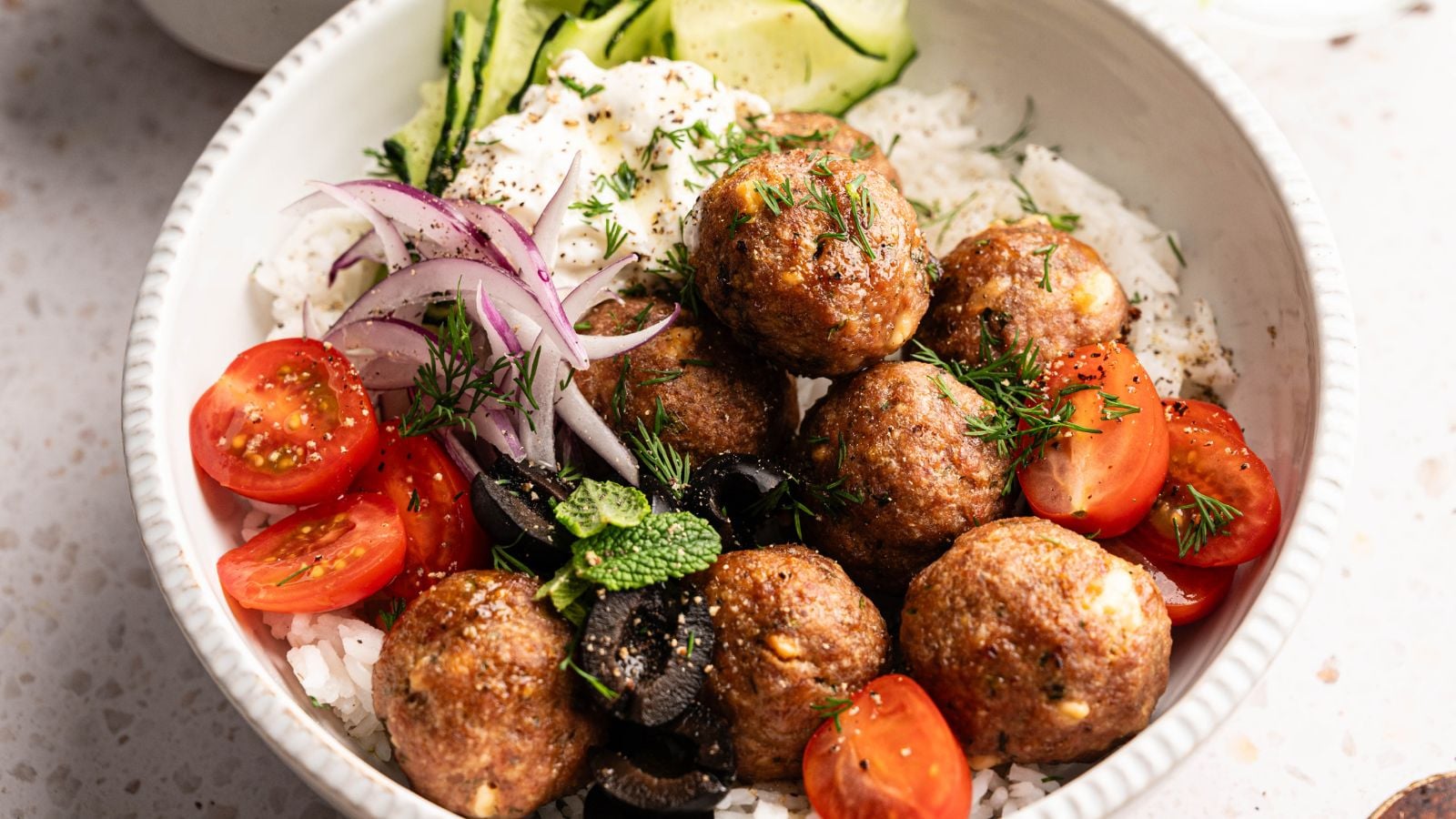 A slice of lasagna with ground meat, tomato sauce, cheese, and chopped herbs on top, served on a white plate with a black fork.