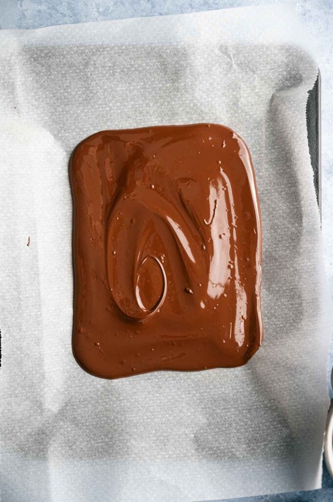 Melted chocolate spread in a rectangular shape on parchment paper, ready to set or be used in a recipe—perfect as the base for festive Shamrock Bark.