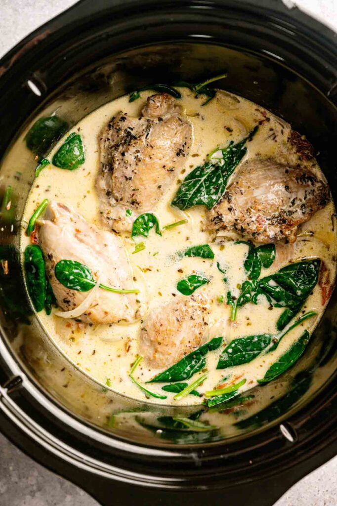 Slow Cooker Chicken Thighs simmered in a creamy herb sauce with fresh spinach, all effortlessly prepared in your slow cooker for a comforting meal.