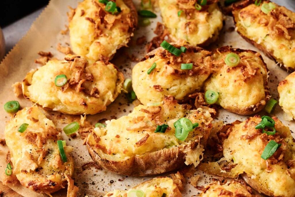 Air Fryer Twice Baked Potatoes topped with crispy onions and chopped green onions, all arranged perfectly on a baking sheet.