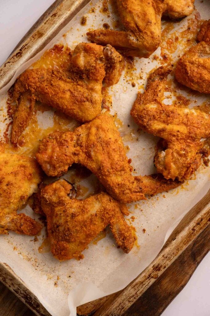 BBQ wings with a crispy, golden-brown coating baked to perfection on a parchment-lined baking sheet.