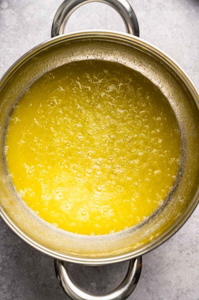 A stainless steel pot filled with melted butter, shown from above on a gray surface&mdash;perfect for starting your Air Fryer Cowboy Cookies.