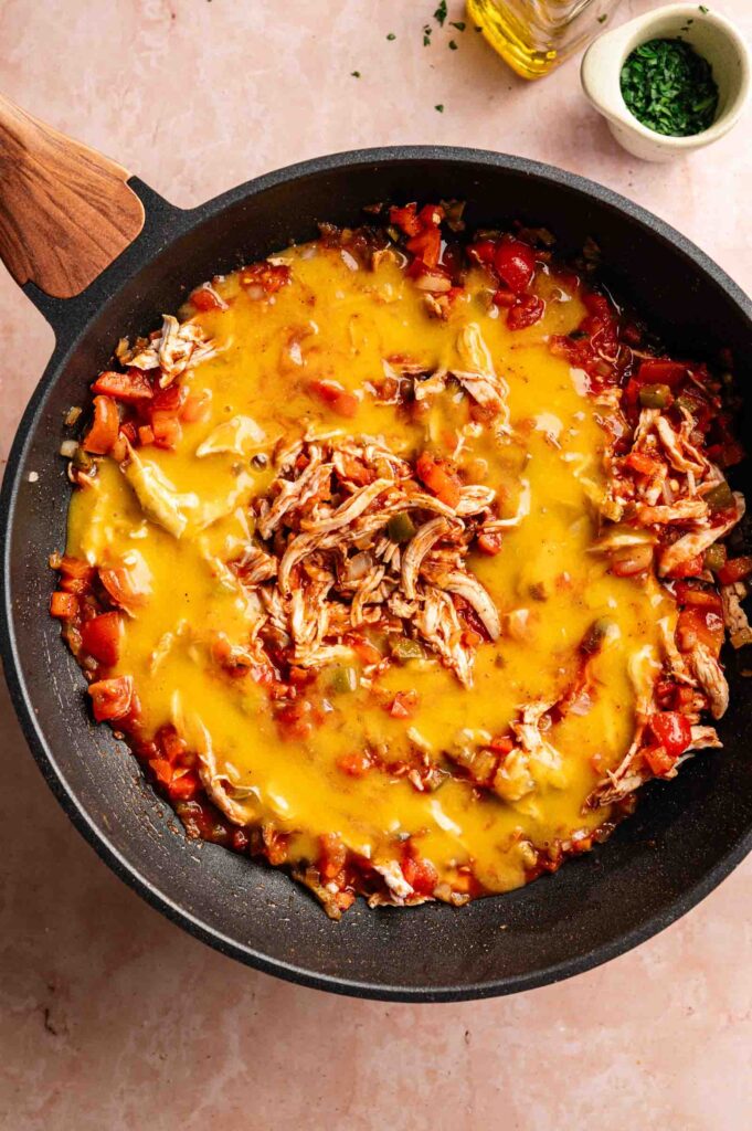 A skillet filled with shredded chicken, diced vegetables, and melted cheese on a light countertop—this classic King Ranch Casserole is comfort food at its finest.