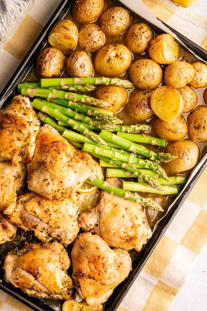 Sheet Pan Chicken Thighs roasted with halved baby potatoes and asparagus spears, all seasoned and baked together for a flavorful one-pan meal.