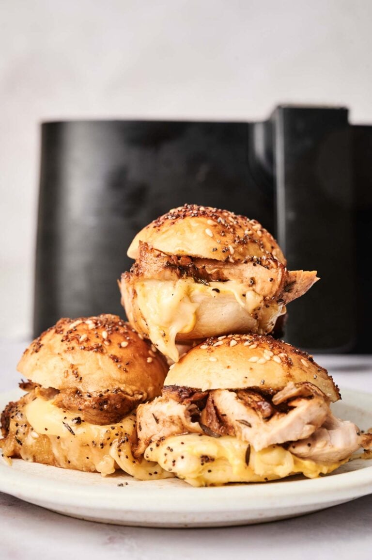 Three sliders on a white plate, with a black air fryer in the background—perfect inspiration for your next batch of Air Fryer Turkey Sliders.